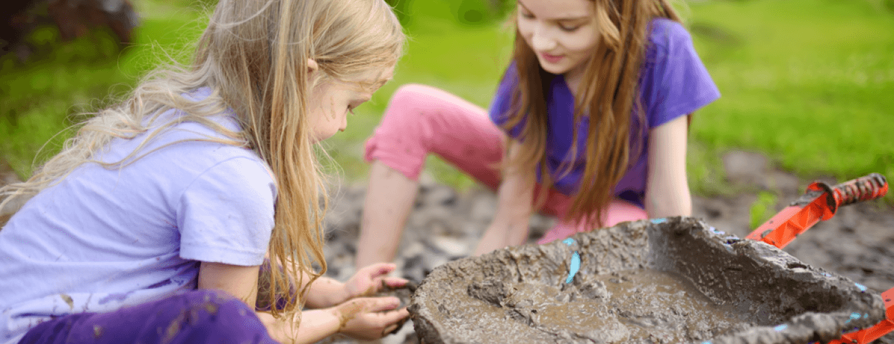 two young girls playing in the mud