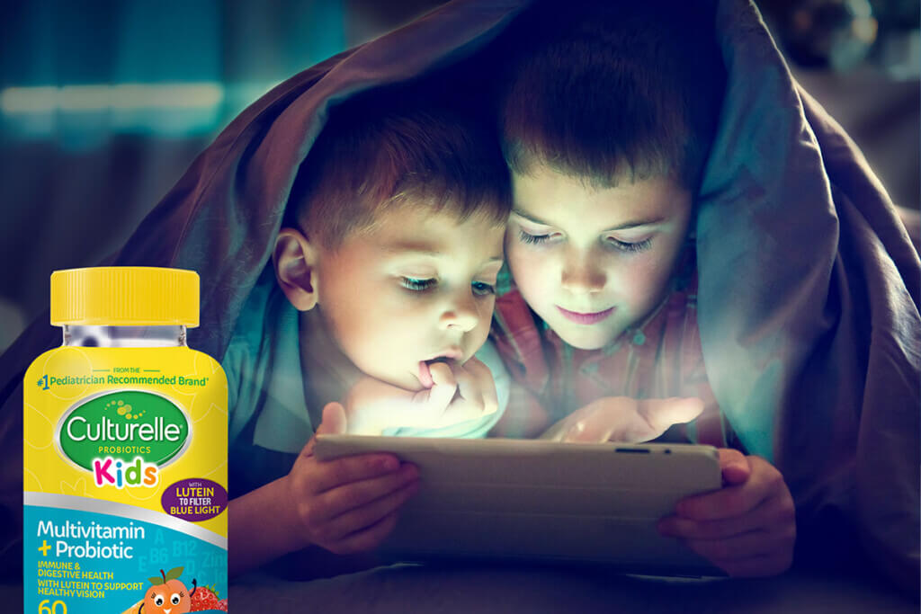 Kids using a tablet under a blanket