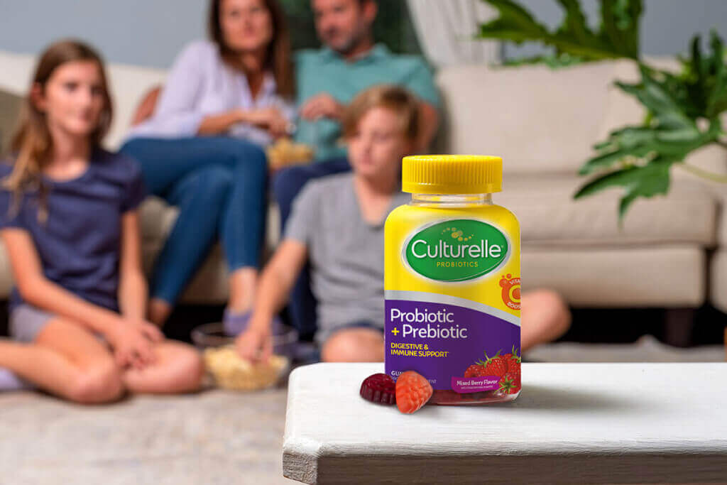 Culturelle gummies bottle with family behind it sitting around a couch